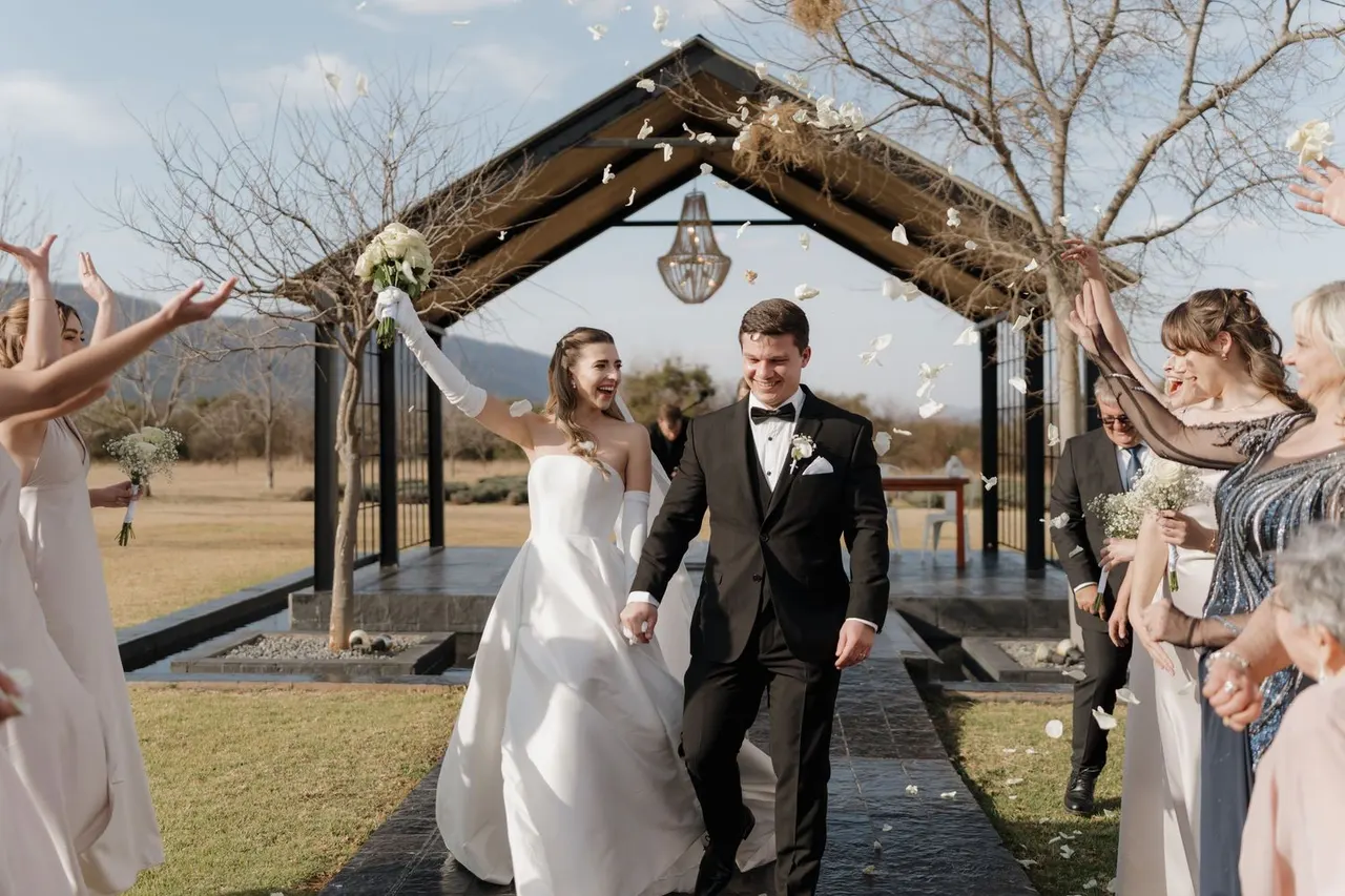 Newlyweds showered with petals leaving a timber chapel