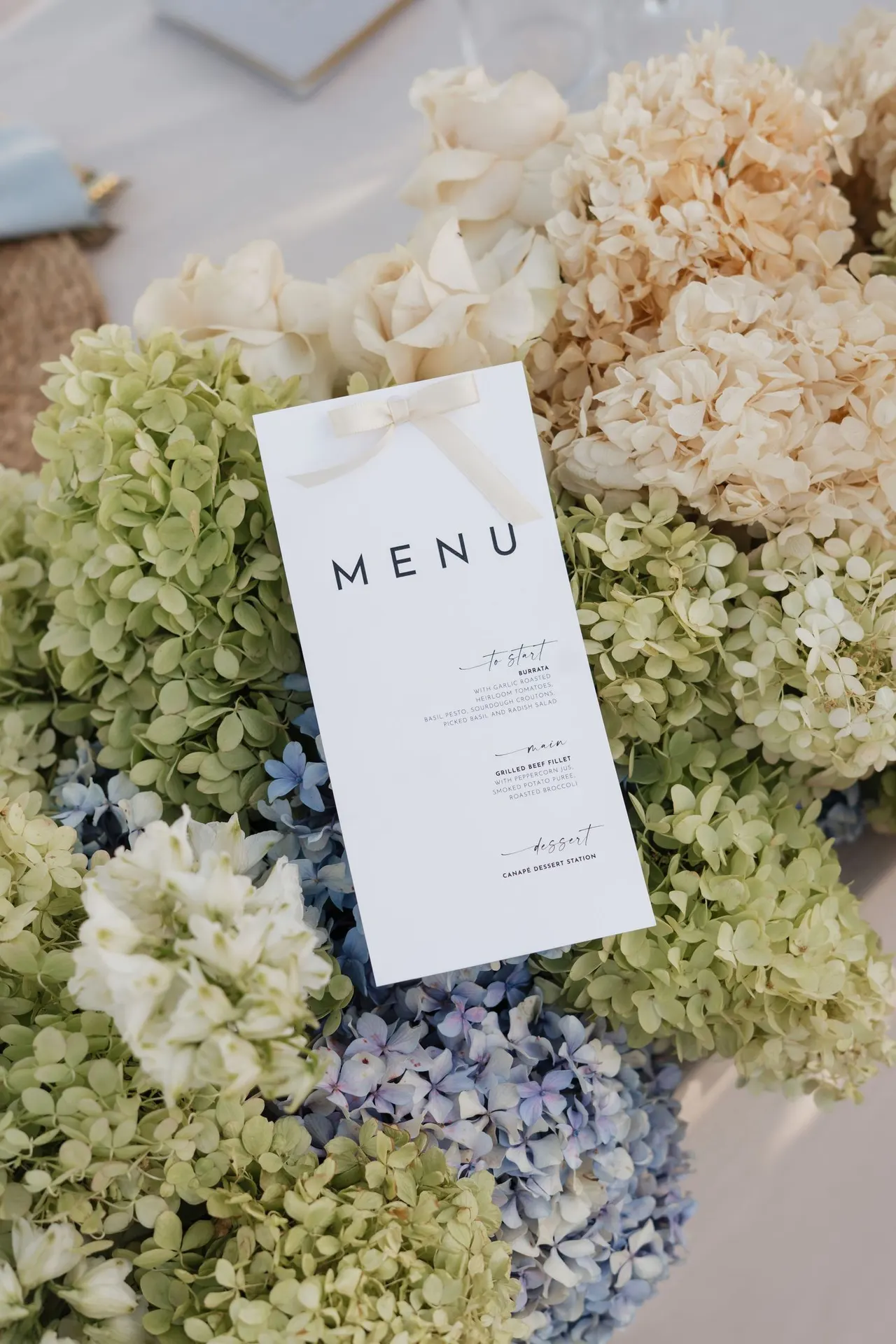 Wedding menu nestled in cream and blue hydrangeas