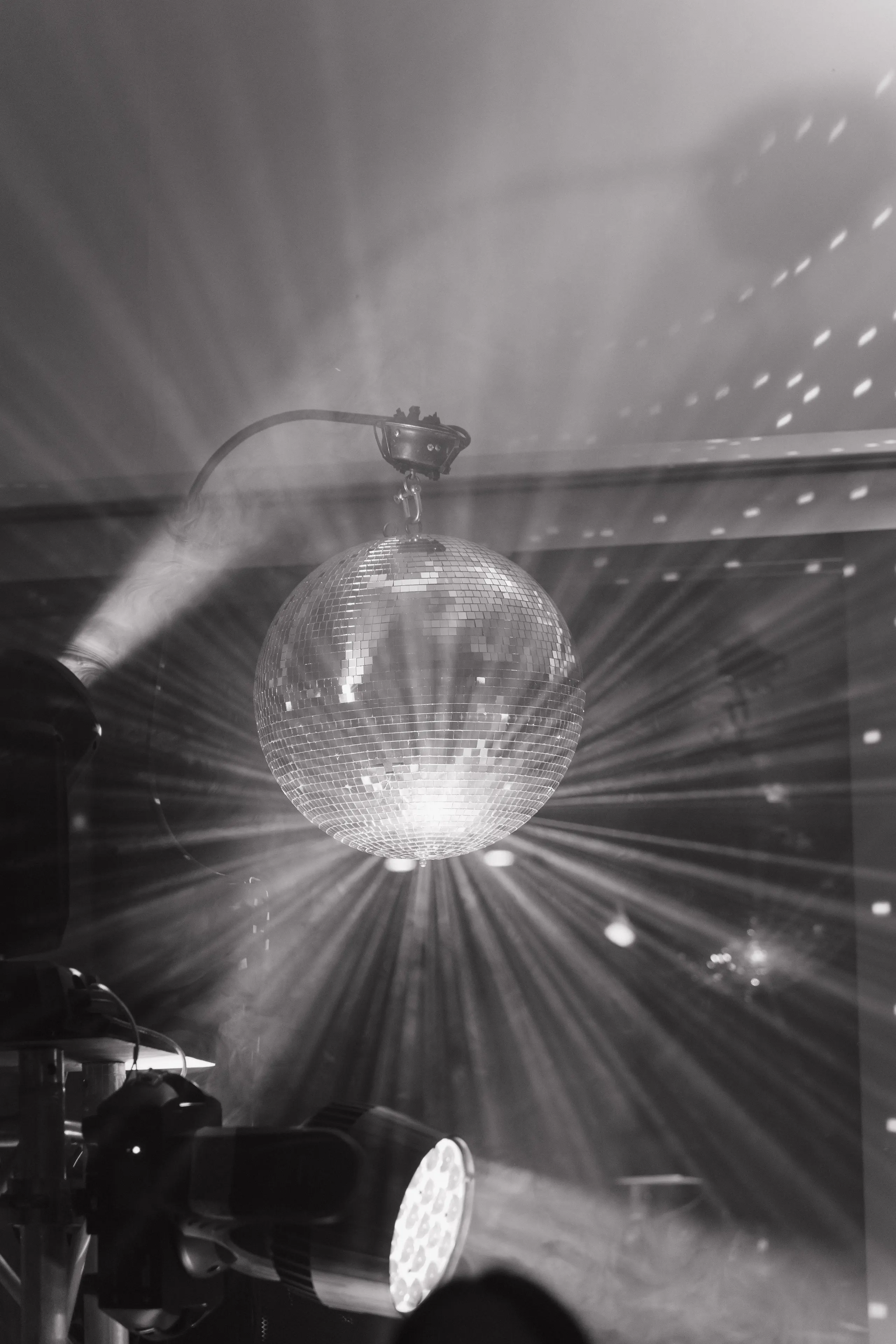 Black-and-white disco ball scattering rays of light across the dance floor