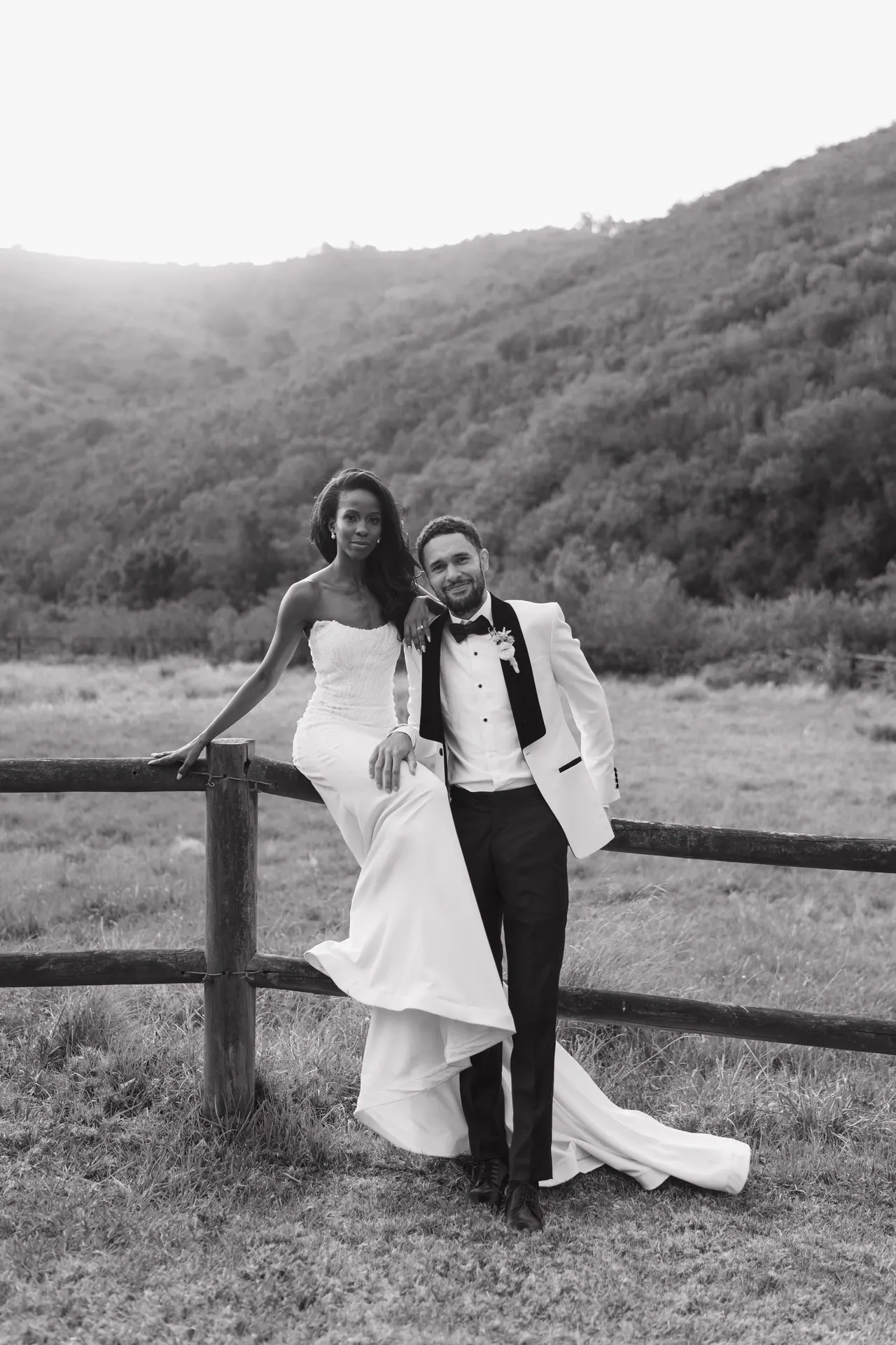 Devon & Lesedi leaning against a farm fence in the mountains