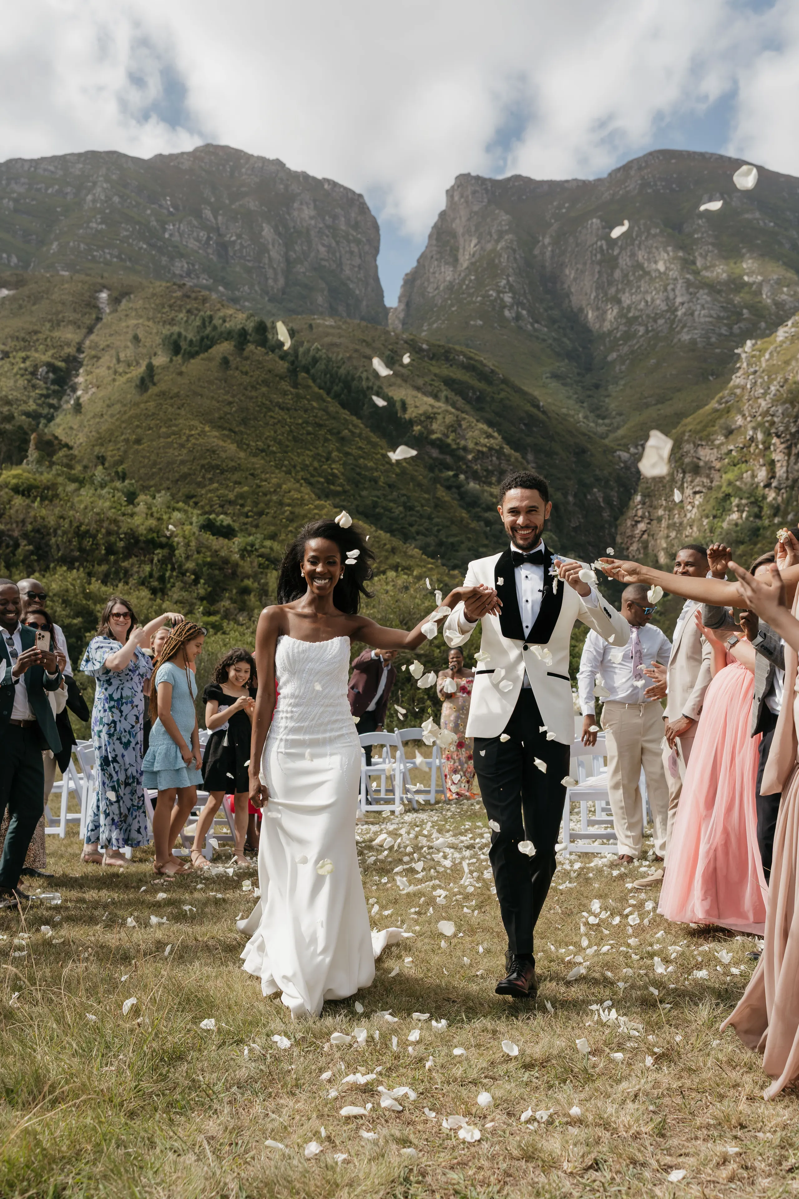 Newlyweds showered with confetti as they walk back up the aisle in the mountains