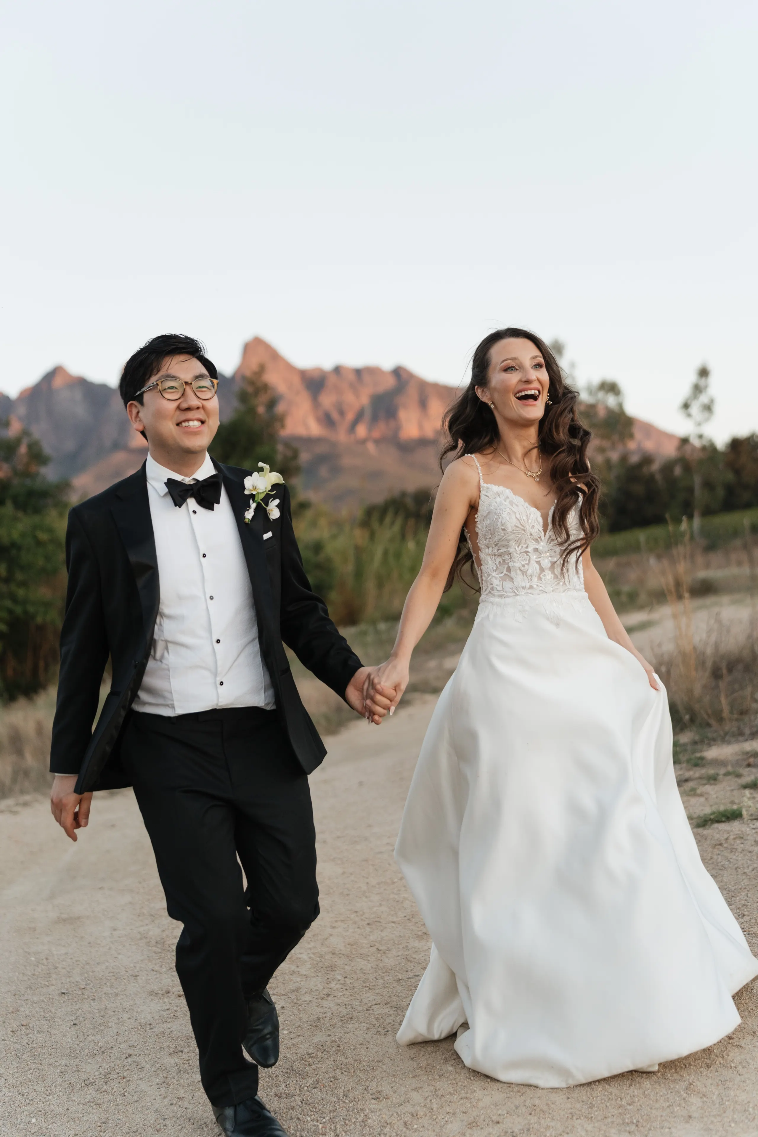 Couple laughing hand in hand on a mountain road after their ceremony
